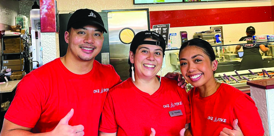 Three Oke Poke staff in red shirts smile and give a thumbs up