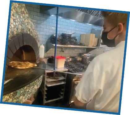 chef putting pizza in oven