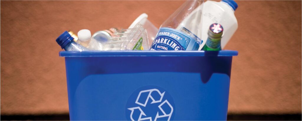 Blue recycling bin filled with recyclables.