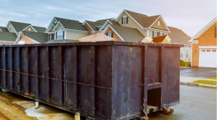 Large construction dumpster on residential street.