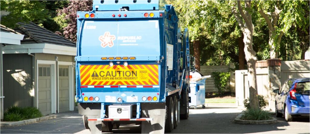 Garbage truck driving through residential street.