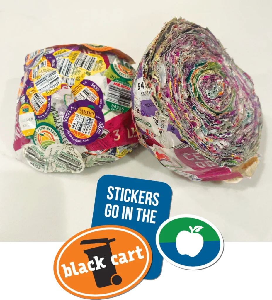 A ball made up of a variety of produce stickers cut in half. Below the balls are fruit-type stickers that make a heading: a blue sticker with white type says "Stickers go in the Black cart"