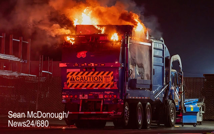 A recycling truck with flames leaping out of the top
