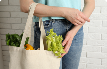 A young person holds a grocery tote.