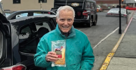 Jack Dice, an elderly white man, holds a package of cheese for food rescue